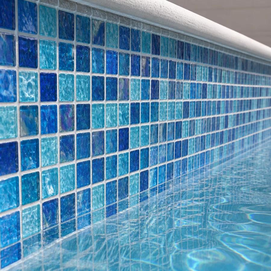 Cận cảnh tường bể bơi ốp gạch mosaic thủy tinh với mạch gọn, thể hiện bề mặt hoàn thiện trong môi trường nước.
