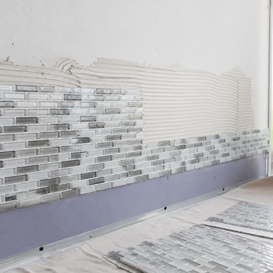 Mosaic đang được dán lên tường theo từng mảng nhỏ, thể hiện thao tác thi công cẩn thận.