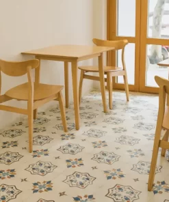 Không gian quán cafe với sàn lát gạch bông Novita OLIVE 6601 hoa văn kem xanh nâu, bàn ghế gỗ sáng màu, ánh sáng tự nhiên, gạch được lát nổi bật dưới bàn ghế
